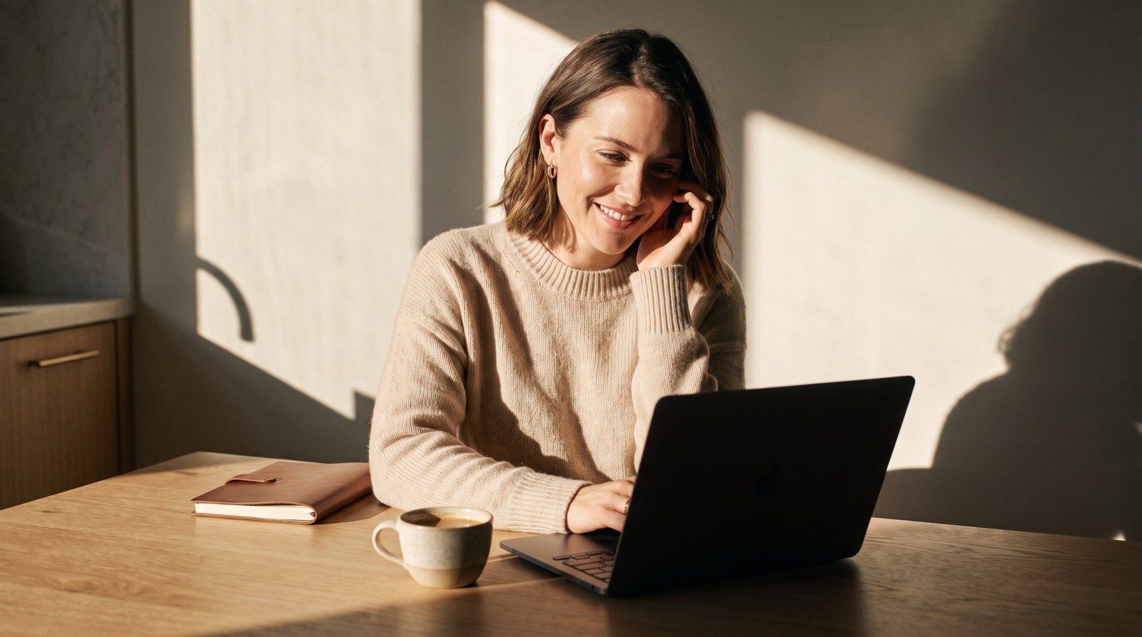 A woman smiling as she looks at job openings on her laptop at home